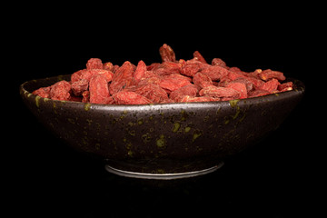 Lot of whole dried red goji in glazed bowl isolated on black glass