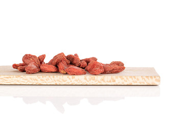 Lot of whole dried red goji on wooden cutting board isolated on white background