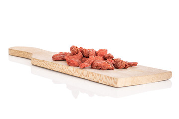 Lot of whole dried red goji on wooden cutting board isolated on white background
