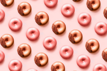 Pattern of d onuts with icing and chocolate on pastel pink background. Sweet donuts.