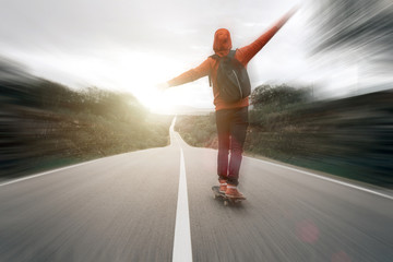 young boy skating down the road on a sunny day