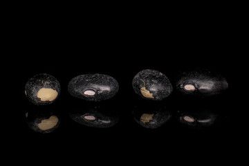 Group of four whole black bean isolated on black glass