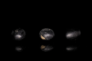 Group of three whole black bean isolated on black glass