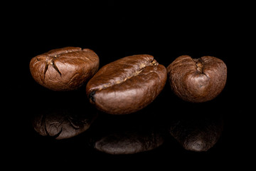 Group of three whole fresh coffee bean isolated on black glass