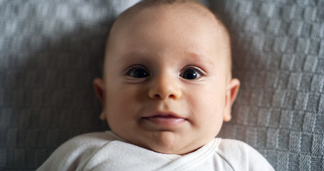 Authentic close up shot of a cute newborn baby is smiling in the camera.  Concept of children,baby, parenthood, childhood, life