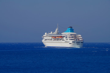 Cruise ship or cruiseship liner tilt or bending in sharp curve on blue sea during dusk or twilight