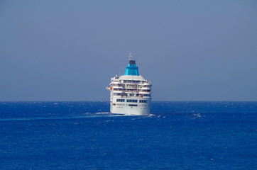 Cruise ship or cruiseship liner tilt or bending in sharp curve on blue sea during dusk or twilight