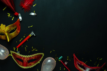Table top view aerial image of beautiful colorful carnival festival background.Flat lay accessory object the several mask & decor confetti on modern black wooden at home office desk studio.copy space.