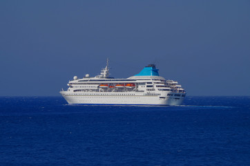 Cruise ship or cruiseship liner tilt or bending in sharp curve on blue sea during dusk or twilight