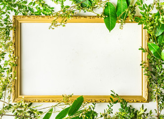 Flat lay with green tree branches and plants on white background with empty picture frame for...