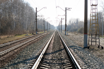 Naklejka na ściany i meble The railway goes into the distance. Rails, sleepers, poles with wires. Spring day