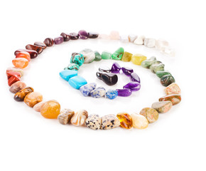 Spiral made of colorful semiprecious gemstones isolated on a white background.