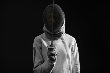 Young female fencer on dark background