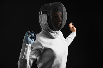 Young female fencer on dark background