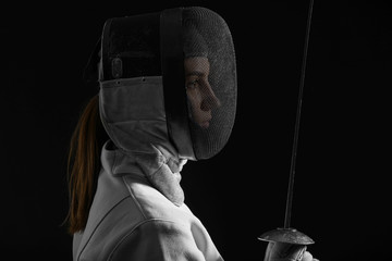 Young female fencer on dark background