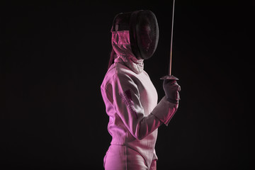 Young female fencer on dark background