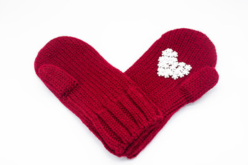 A knitted red mittens with white snowflakes in the shape of a heart on a white background, isolated. Concept of Christmas, winter, love. Care and Valentine's day. Copy space