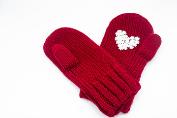 A knitted red mittens with white snowflakes in the shape of a heart on a white background, isolated. Concept of Christmas, winter, love. Care and Valentine's day. Copy space