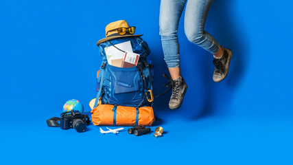 .Tourist planning vacation with the help of world map with other travel accessories around. Woman traveler with suitcase on Blue color background. Concept travel backpack