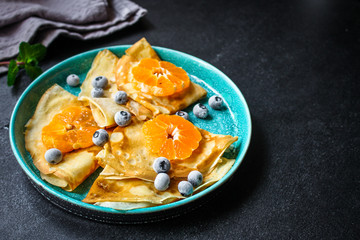 crepes with citrus, jam and berries (thin pancakes, mandarin, blueberry) menu concept. background. top view. copy space