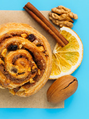 Cinnamon bun with nuts and lemons on a blue background