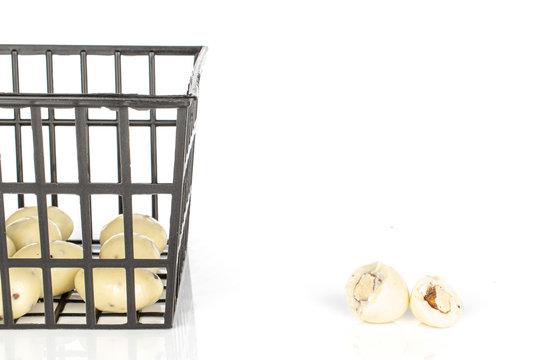 Group of lot of whole two halves of coated white almond nut stracciatella in black plastic basket isolated on white background