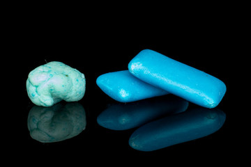 Group of two whole blue chewing gum with one bolus isolated on black glass