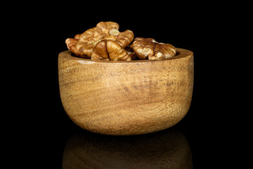 Lot of whole tasty brown pecan half in bamboo bowl isolated on black glass