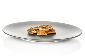 Lot of whole tasty brown pecan half on gray ceramic plate isolated on white background
