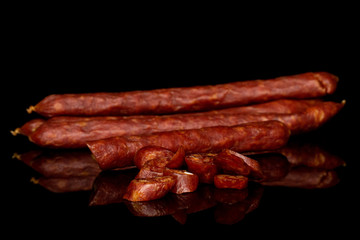Group of two whole one quarter lot of slices of piquant smoked sausage isolated on black glass