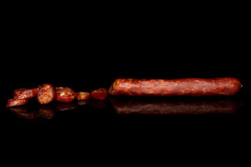 One half lot of slices of piquant smoked sausage isolated on black glass