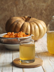 The use of pumpkin and pumpkin juice. Use in medicine. Juice in a glass glass on a wooden background.