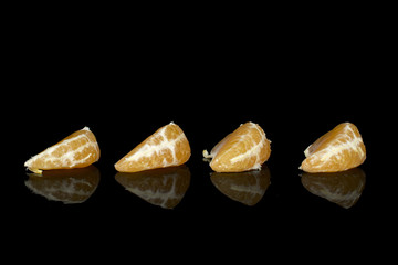 Group of four pieces of peeled fresh orange mandarin line isolated on black glass
