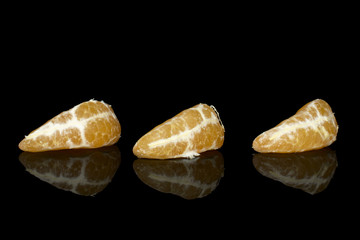 Group of three pieces of peeled fresh orange mandarin isolated on black glass