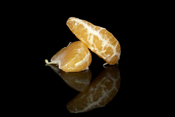 Group of two pieces of peeled fresh orange mandarin isolated on black glass