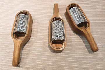 three graters for vegetables lie on a linen tablecloth