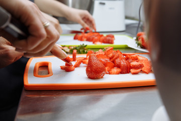 Obraz na płótnie Canvas woman slices fresh strawberries with a knife