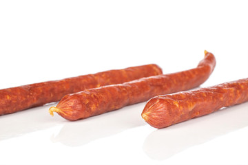 Group of three whole piquant smoked sausage isolated on white background