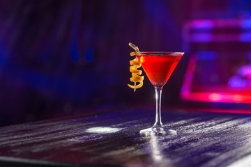 Red cosmopolitan cocktail with orange peel on the table on nightclub background - obrazy, fototapety, plakaty