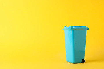 Blue recycle bin on yellow background, space for text