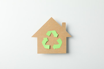 Cardboard house with recycling sign on white background, space for text