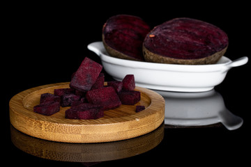 Group of two halves lot of pieces of raw sweet beetroot on round bamboo coaster on white ceramic...