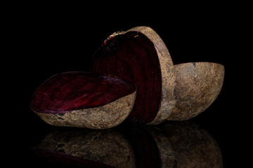 Group of two halves one slice of raw sweet beetroot isolated on black glass