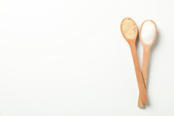 Wooden spoons with sugar on white background, top view