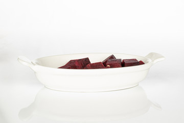 Lot of pieces of raw sweet beetroot on white ceramic plate isolated on white background