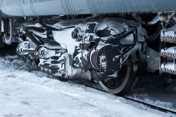 ice covered bogie of a railway passenger carriage on rails in winter