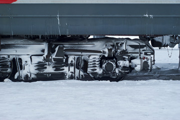 ice covered bogie of a railway passenger carriage on rails in winter