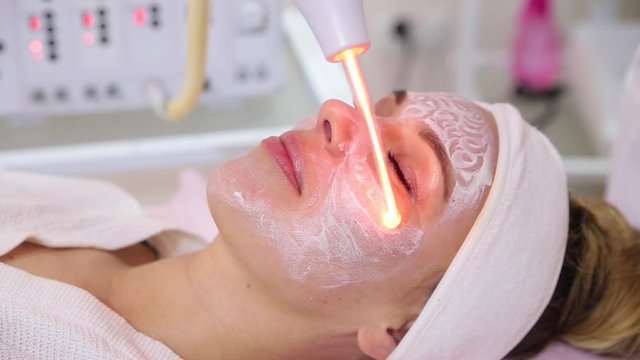 Receiving electric darsonval facial massage procedure.