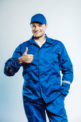Portrait of young worker man wearing blue uniform. Showing thumb up. Movement cool. Isolated on...