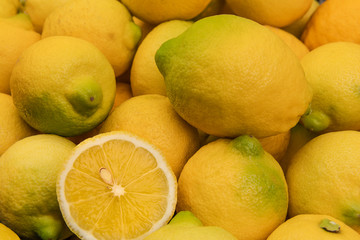 Background of fresh whole lemons and one of them half cut